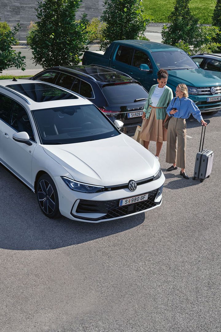 Zwei Frauen stehen auf einem Parkplatz neben einem weißen VW Passat B9