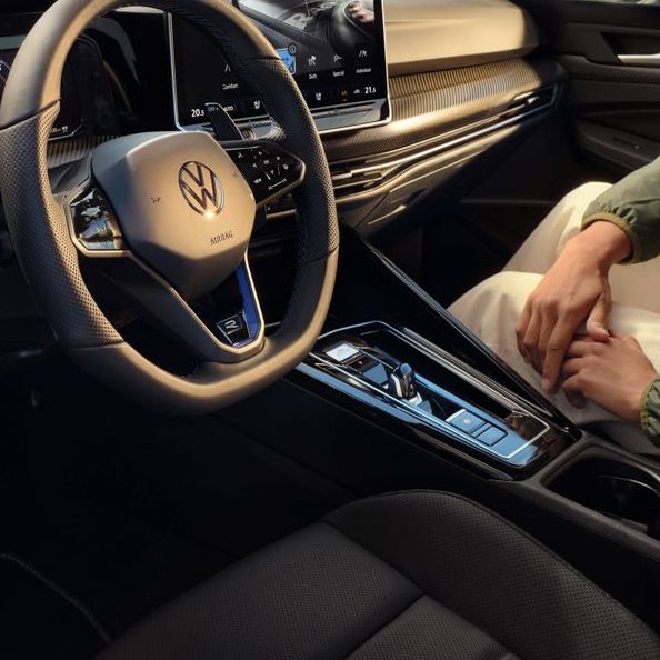 Sicht von geöffneter Fahrertür auf das Interior des Golf R mit einer Frau, welche auf dem Beifahrersitz ist.