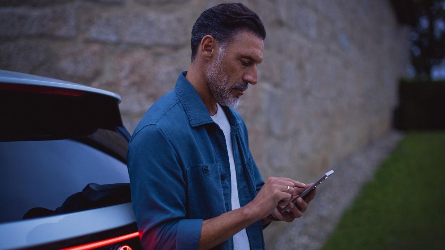 Mann steht am Tayron und schaut auf sein Handy