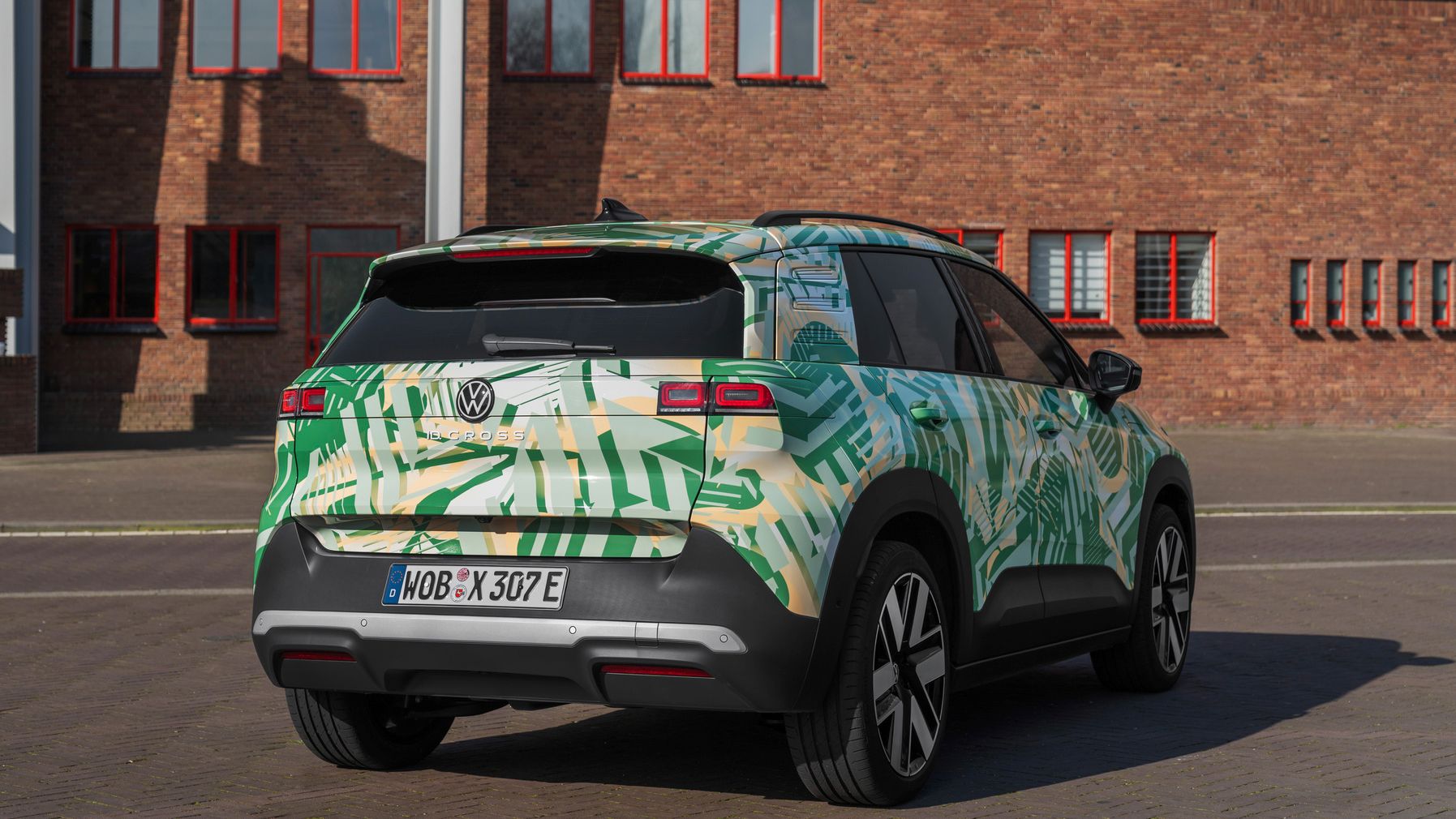 Ein Volkswagen SUV steht vor einem Backsteingebäude. Das Auto hat eine grüne und weiße Tarnlackierung und deutsche Kennzeichen. Es ist von hinten und leicht von der Seite zu sehen.