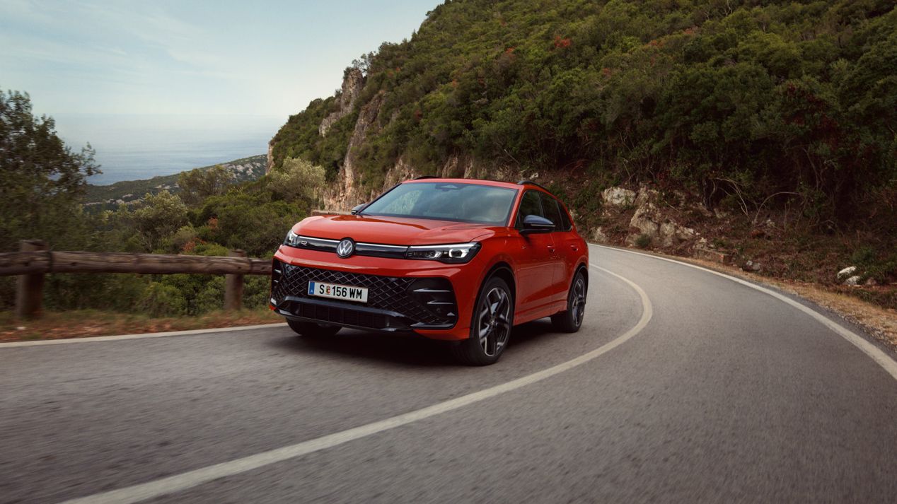 Roter VW Tiguan R-Line fährt eine kurvige Straße entlang.