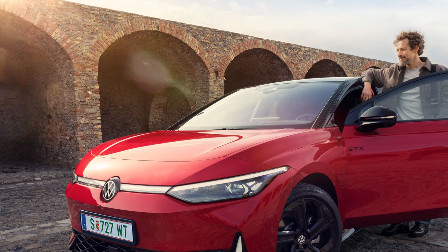 Frontansicht eines roten ID.7 GTX, ein Mann steht in der Fahrertür des Autos. 