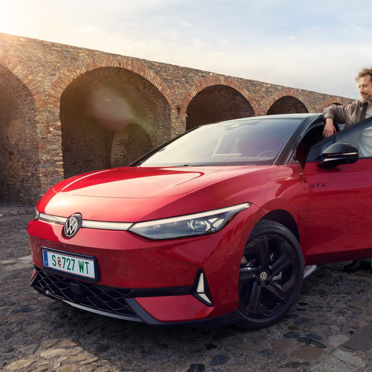 Frontansicht eines roten ID.7 GTX, ein Mann steht in der Fahrertür des Autos. 