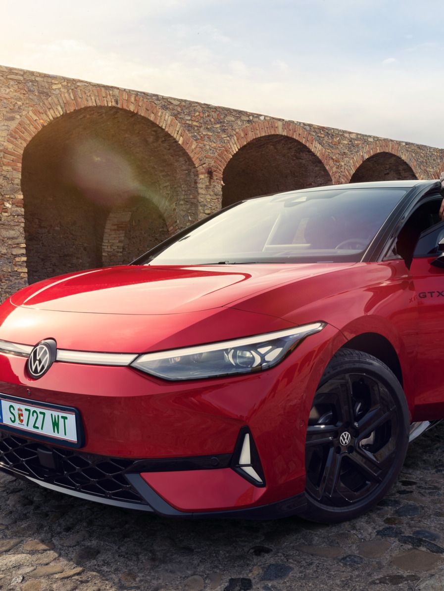 Frontansicht eines roten ID.7 GTX, ein Mann steht in der Fahrertür des Autos. 