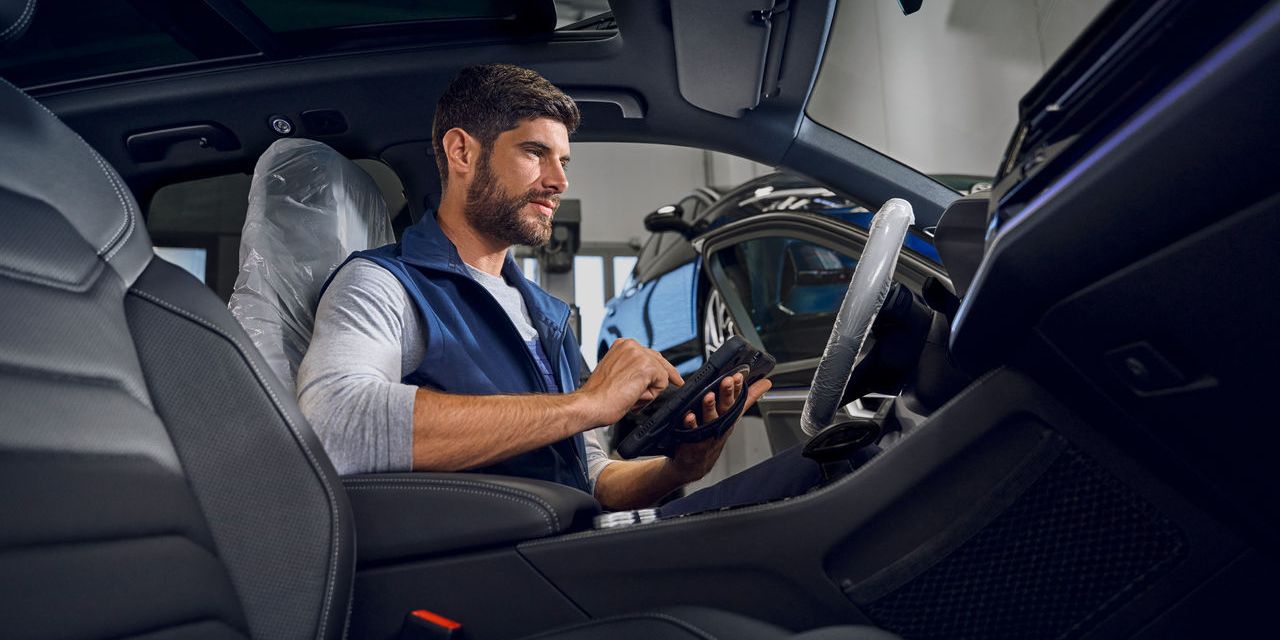 Ein Volkswagen Techniker mit Prüfgerät sitzt in einem Volkswagen Touareg