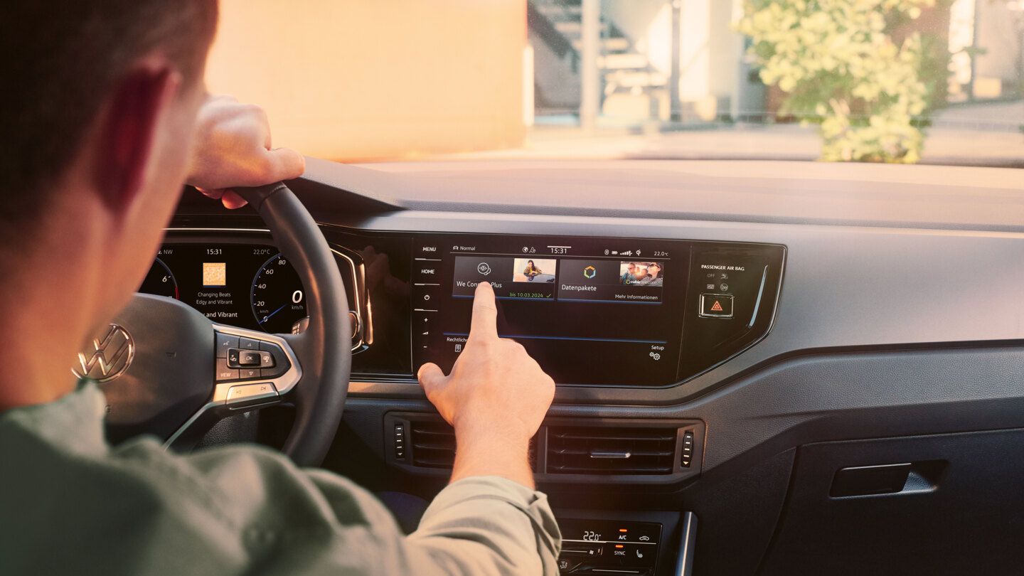 Ein Mann sitzt am Steuer eines VW Polo R-Line und bedient das Infotainment-System mit dem Menü der Upgrade-Funktionen.