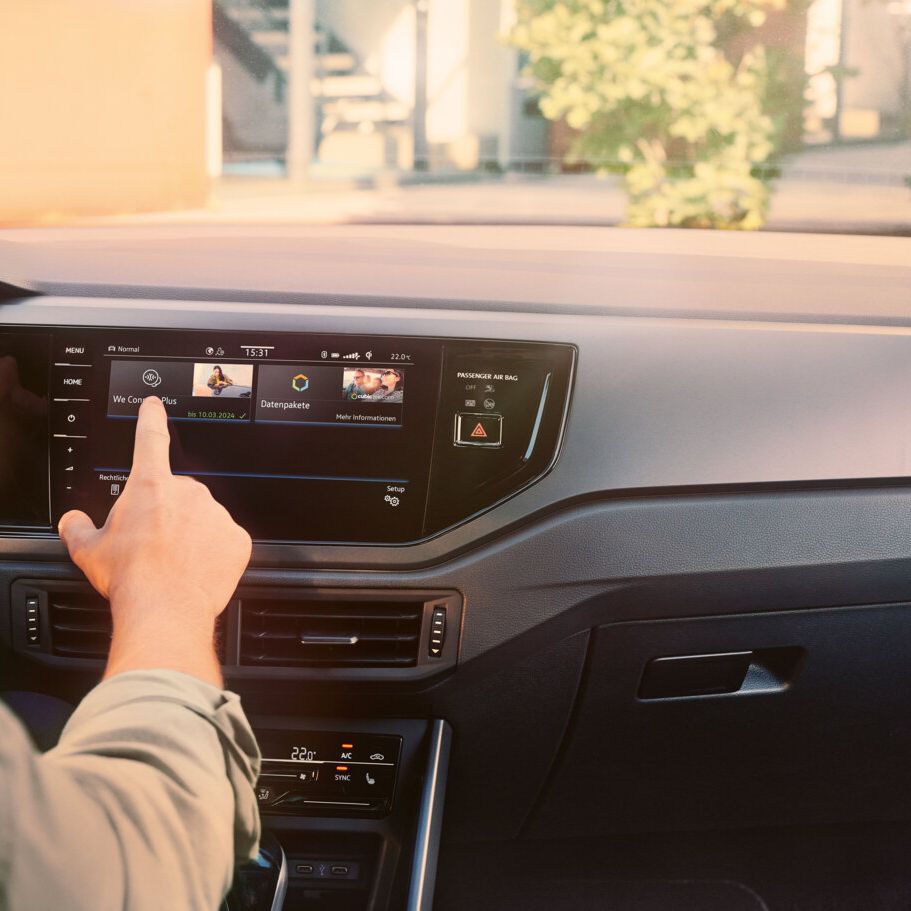 Ein Mann sitzt am Steuer eines VW Polo R-Line und bedient das Infotainment-System mit dem Menü der Upgrade-Funktionen.