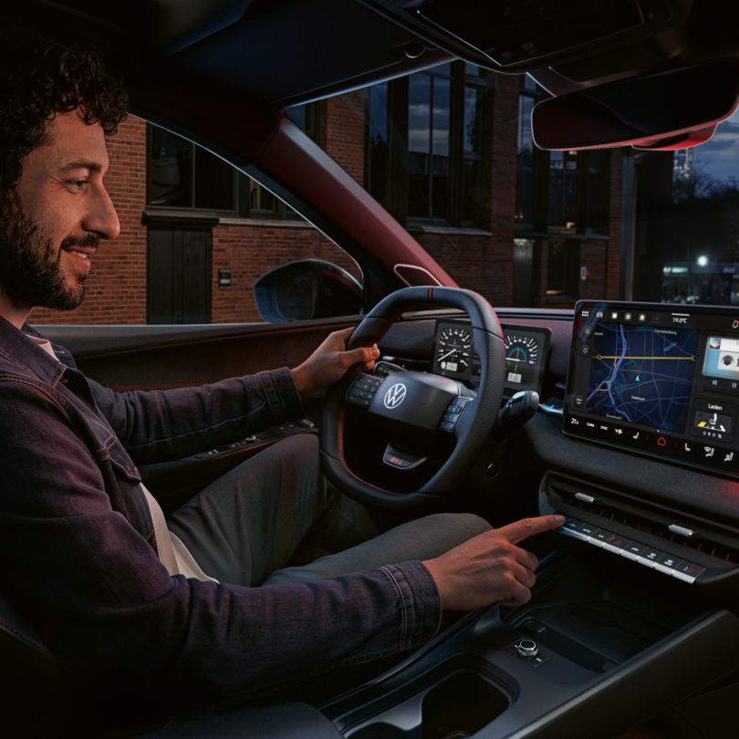Eine Person bedient einen Knopf des Infotainment-Systems im VW ID. Polo GTI.