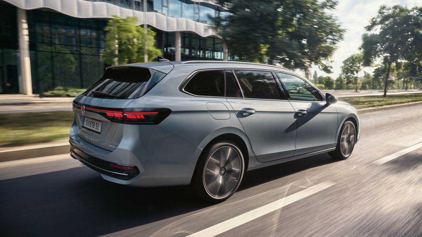 Ein VW Passat Elegance Plug-In-Hybrid fährt vor einem modernen Gebäude in urbaner Umgebung.