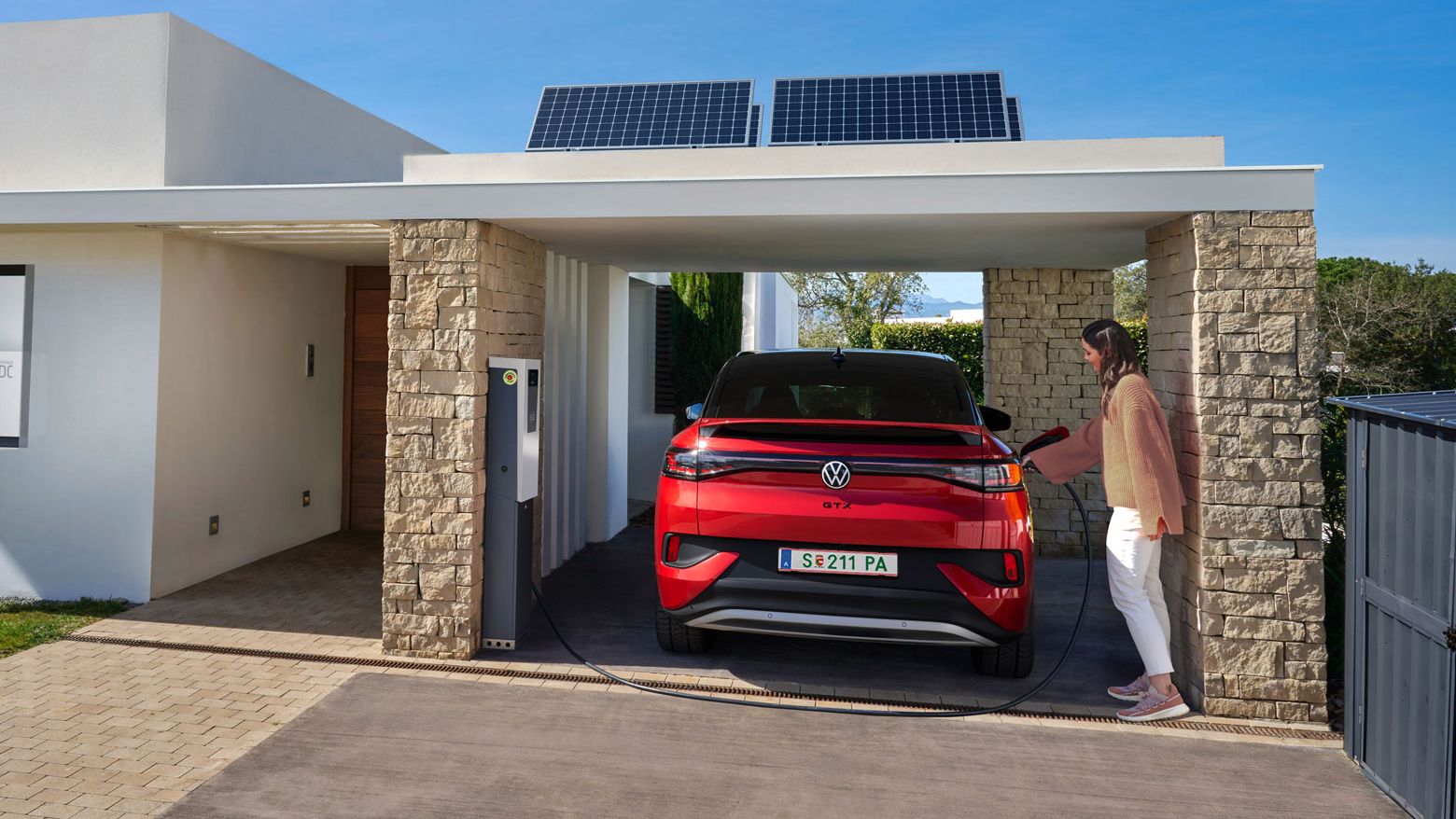 Frau steckt gerade ihren ID.5 GTX im Carport an.