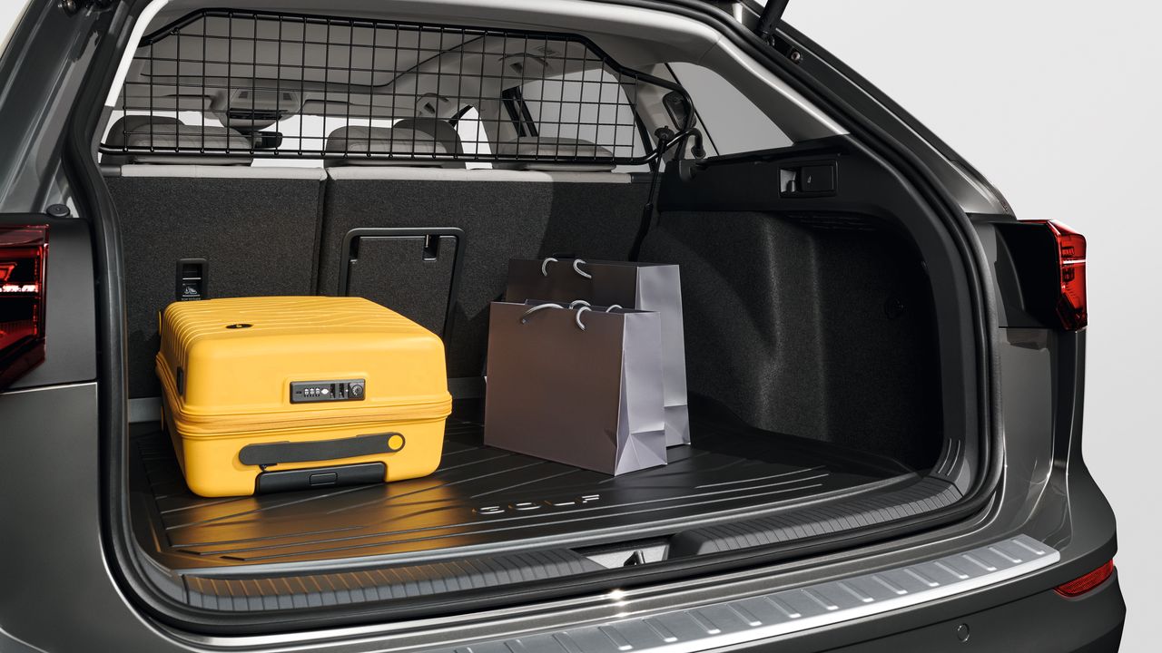 Blick in den geöffneten Kofferraum eines Volkswagen mit Trenngitter. Im Kofferraum liegt ein gelber Koffer und zwei Tragtaschen.
