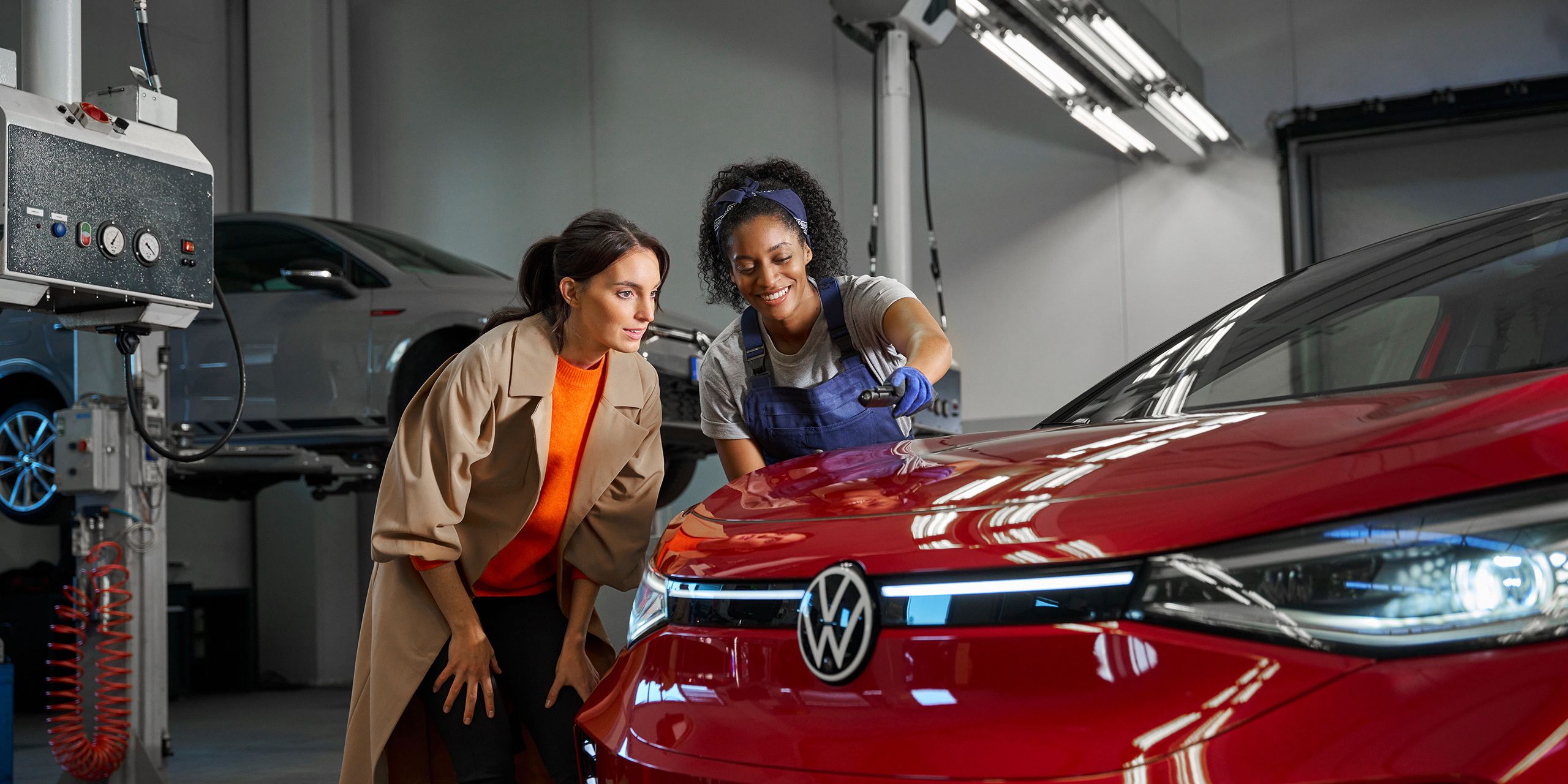 Eine Volkswagen Technikerin erklärt einer Kundin die Lackreparatur