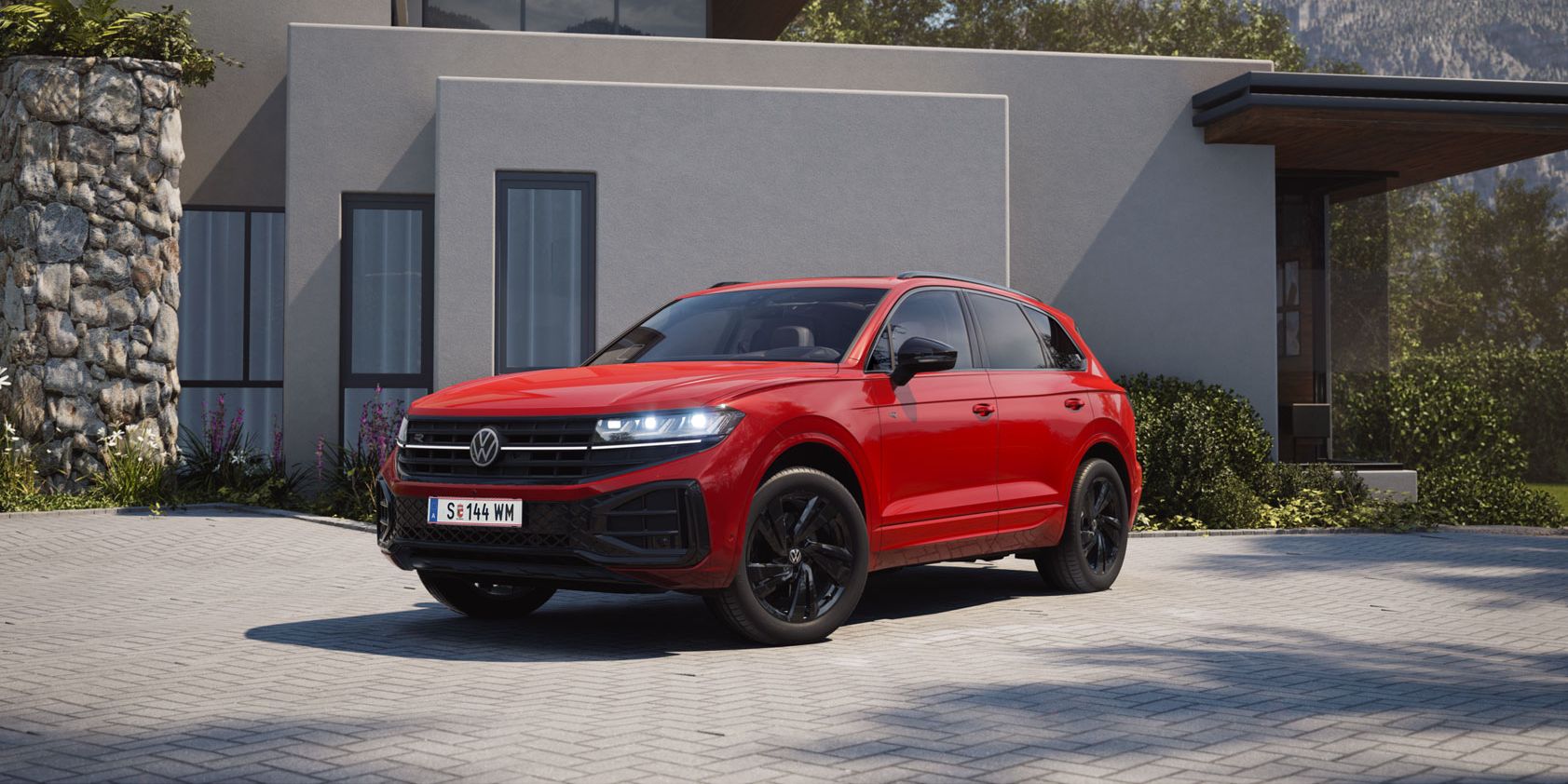 Blick von der Front über die Seite auf einen roten VW Touareg mit R-Line „Exterieur Black Style“-Elementen.