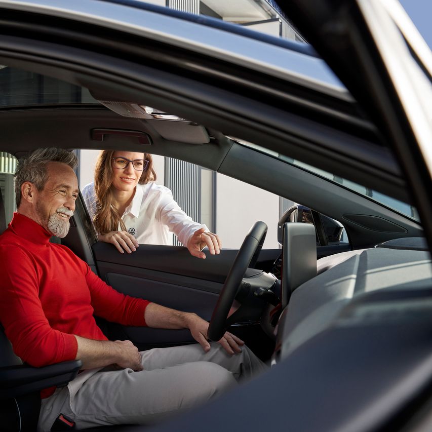 Ein Mann sitzt am Steuer eines Volkswagen und lächelt