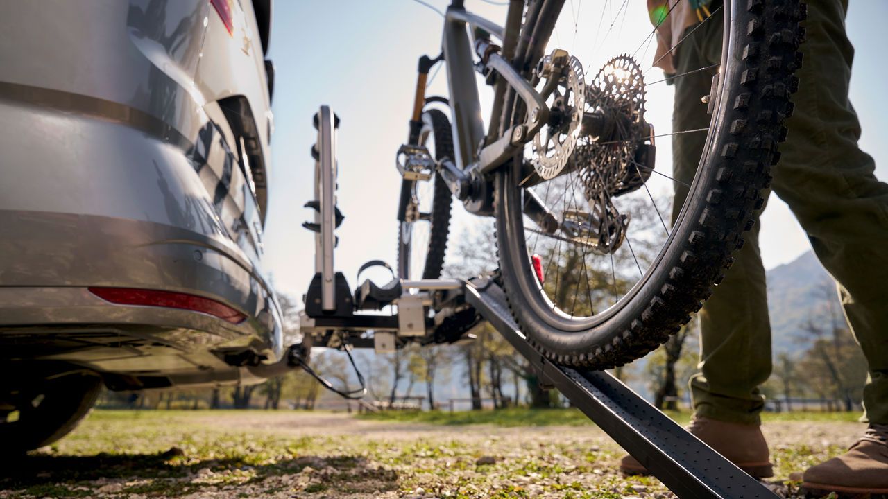 Ein Mann befestigt ein Fahrrad an einem Volkswagen Fahrrad Heckträger.