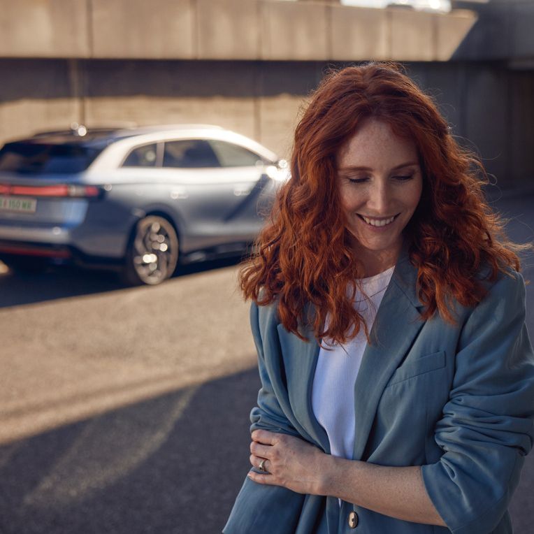 Frau mit einem Lächeln steht vor dem ID.7 Tourer 