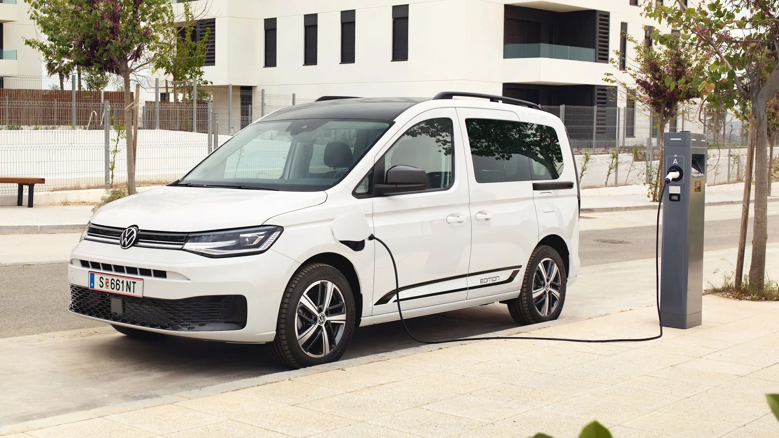 Ein weißer VW Caddy eHybrid steht an einer Ladesäule.