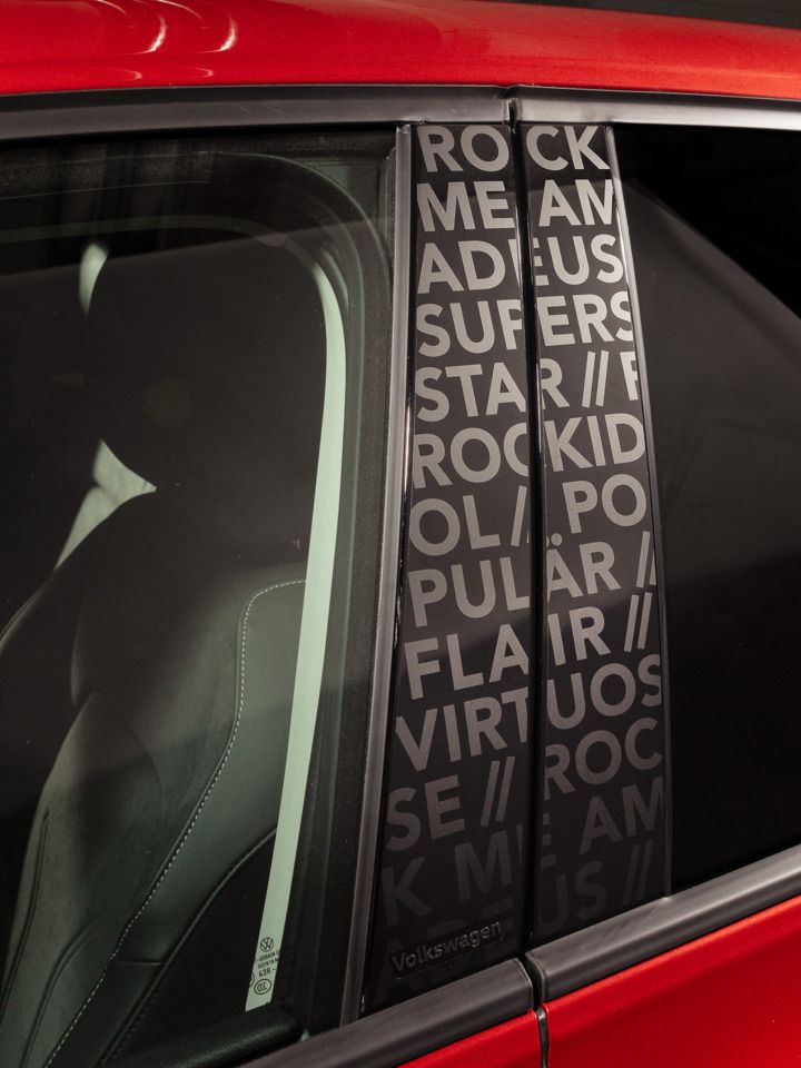 Detailaufnahme der B-Säule eines roten VW Golf Falco Edition. Zu sehen ist dort der Song "Rock me Amadeus", sowie die Worte Superstar, Rockidol, Flair & Virtuose.