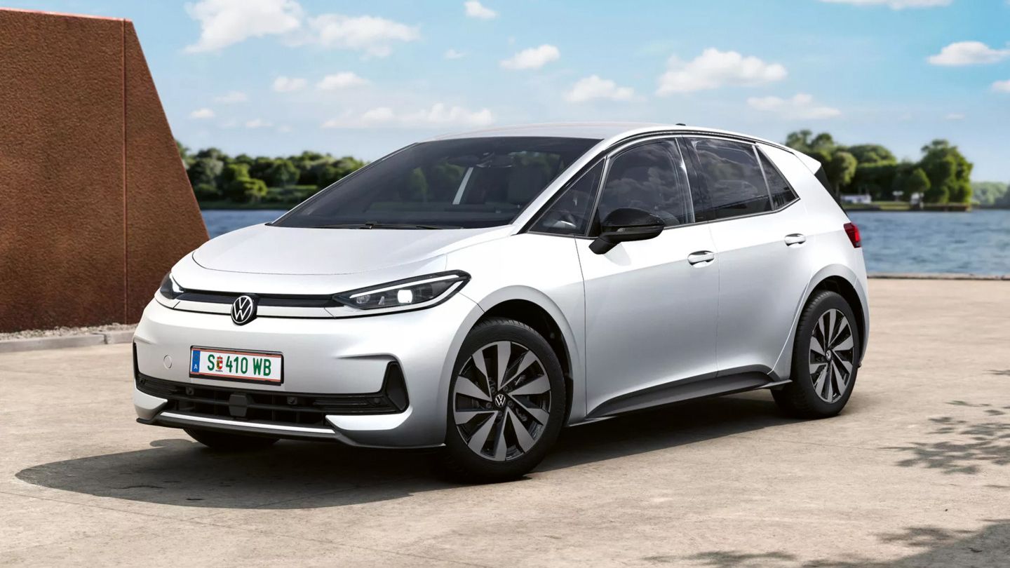 Weißer ID.3 Neo mit fünf Türen steht auf einer betonierten Fläche an einem Gewässer, im Hintergrund Bäume und blauer Himmel mit wenigen Wolken. Das Auto wirkt vollelektrisch, mit aerodynamischen Felgen und schmalen LED-Scheinwerfern.