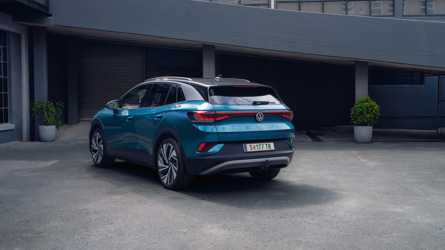 Blauer VW ID.4 in Heckansicht parkt im Innenhof eines industriellen Gebäudes.