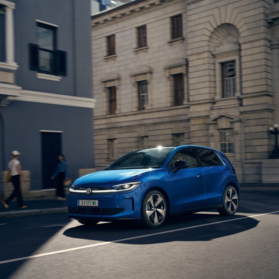 Ein blauer VW ID. Polo Style fährt durch eine Stadt.