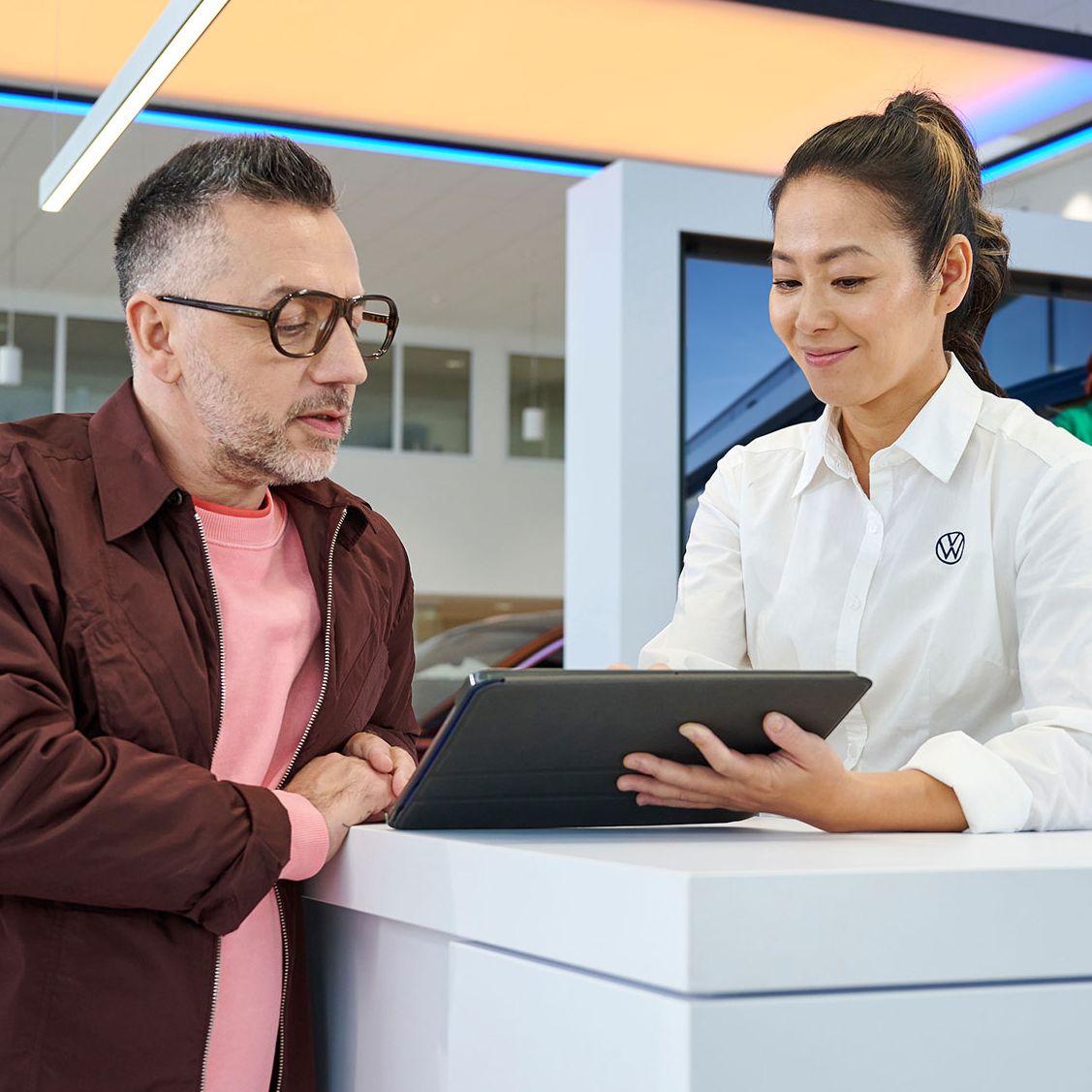 Eine Frau gibt einem Mann mithilfe eines Tablets Informationen.