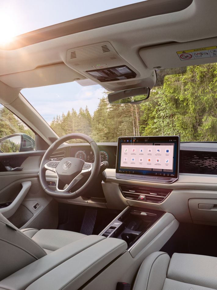 Blick in das helle Interieur des VW Passat Elegance inkl. Panoramadach, Infotainmentsystem, Mittelkonsole, Lenkrad und Sitze.