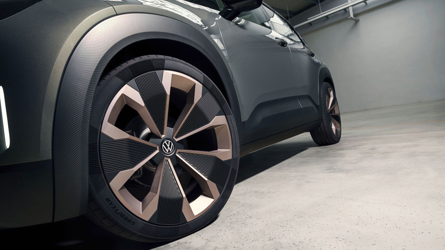 Bild des VW ID. Cross Concept. Auf dem Bild sieht man den linken Vorderreifen im Vordergrund sowie das das linke Exterieur des Autos. Das Auto steht in einer Art Halle.