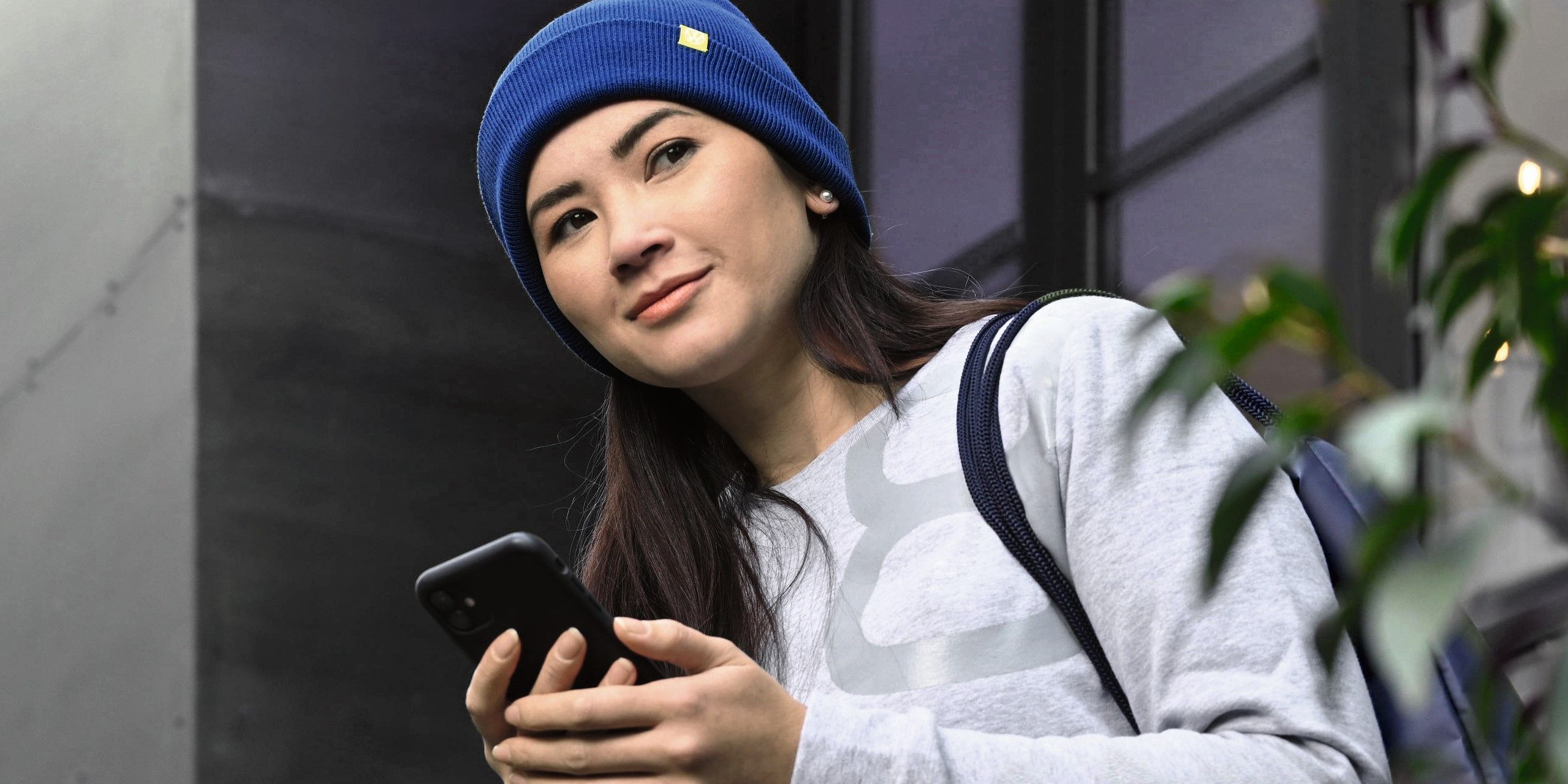 Eine Frau mit Smartphone steht in einem Hauseingang