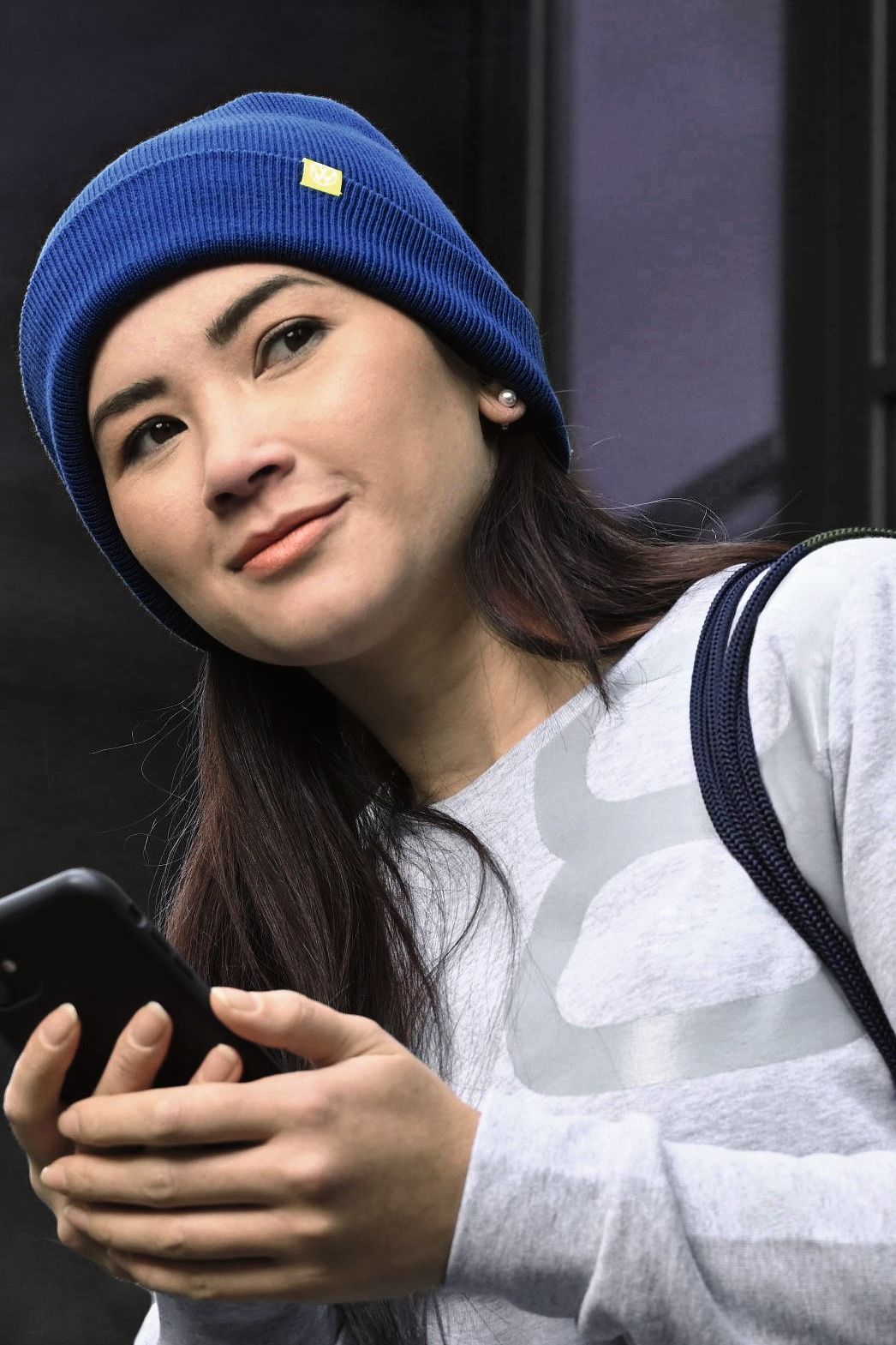 Eine Frau mit Smartphone steht in einem Hauseingang