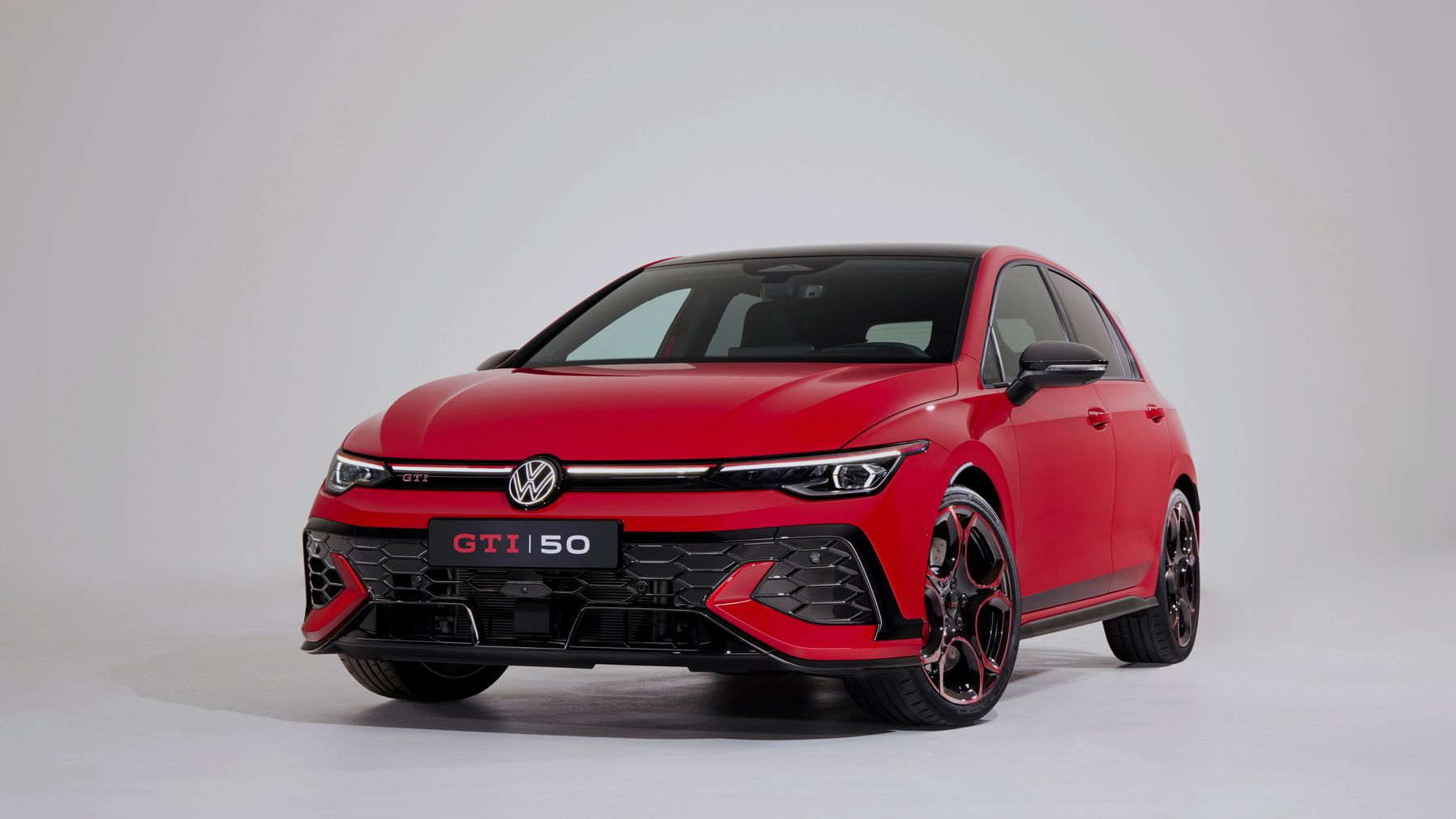 Ein roter Volkswagen GTI 50 steht auf einem weißen Hintergrund. Das Fahrzeug hat eine sportliche Optik und auffällige schwarze und rote Felgen. Der GTI-Schriftzug und die Zahl 50 sind auf dem Kennzeichen zu sehen.