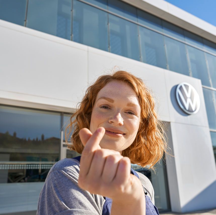 Volkswagen Service Mitarbeiterin vor dem Eingang zu einem Volkswagen Service Partner