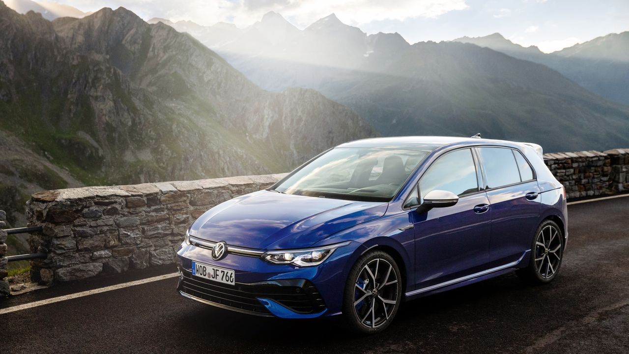 Ein blauer VW Golf 8 R Vorgänger vor einem Bergpanorama
