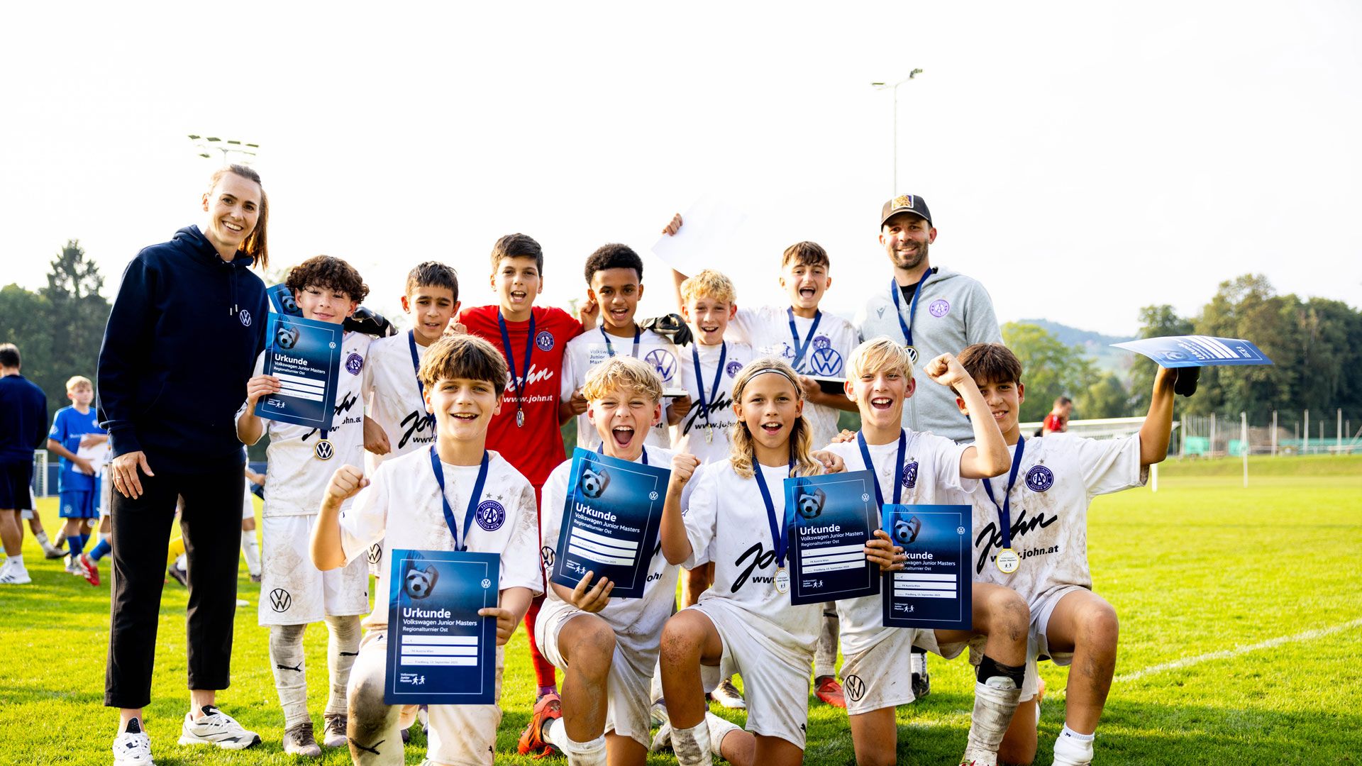Ein junges Fußballteam feiert ihren Sieg beim VW Junior Masters Regionalturnier mit Urkunden 