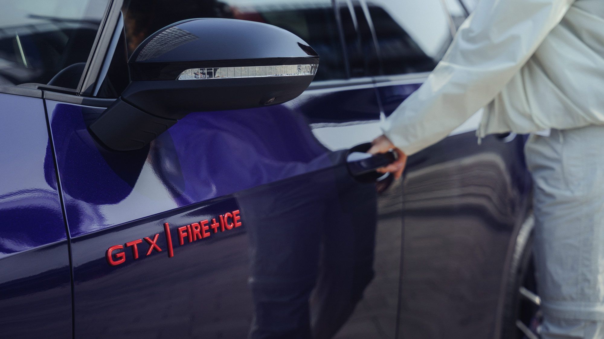 Eine Person öffnet die Tür eines lilafarbenen ID.3 GTX FIRE+ICE. Auf dem Auto befindet sich der Schriftzug "GTX FIRE+ICE". Die Person trägt helle Kleidung.