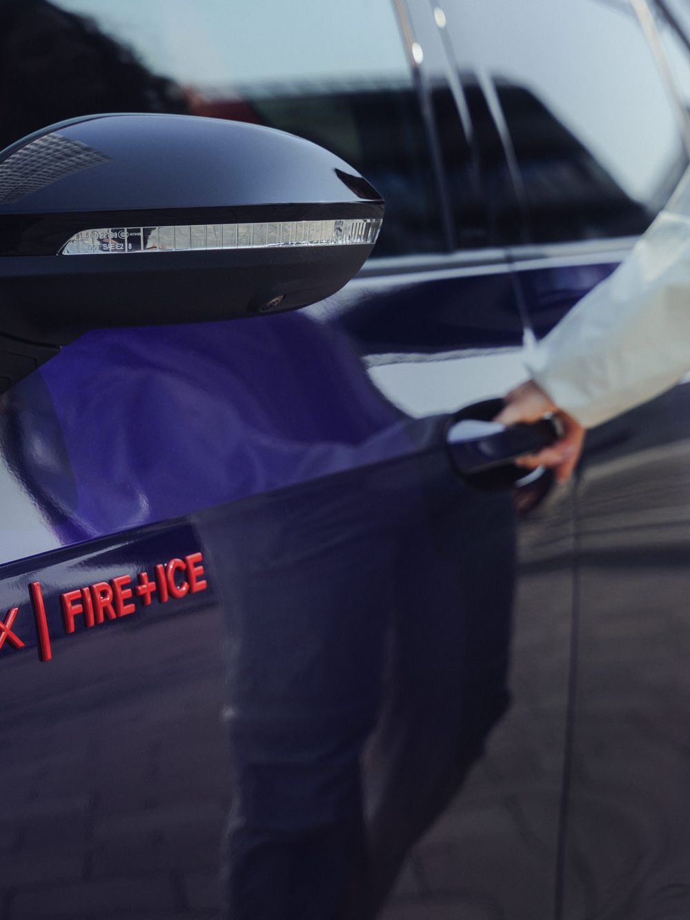 Eine Person öffnet die Tür eines lilafarbenen ID.3 GTX FIRE+ICE. Auf dem Auto befindet sich der Schriftzug "GTX FIRE+ICE". Die Person trägt helle Kleidung.