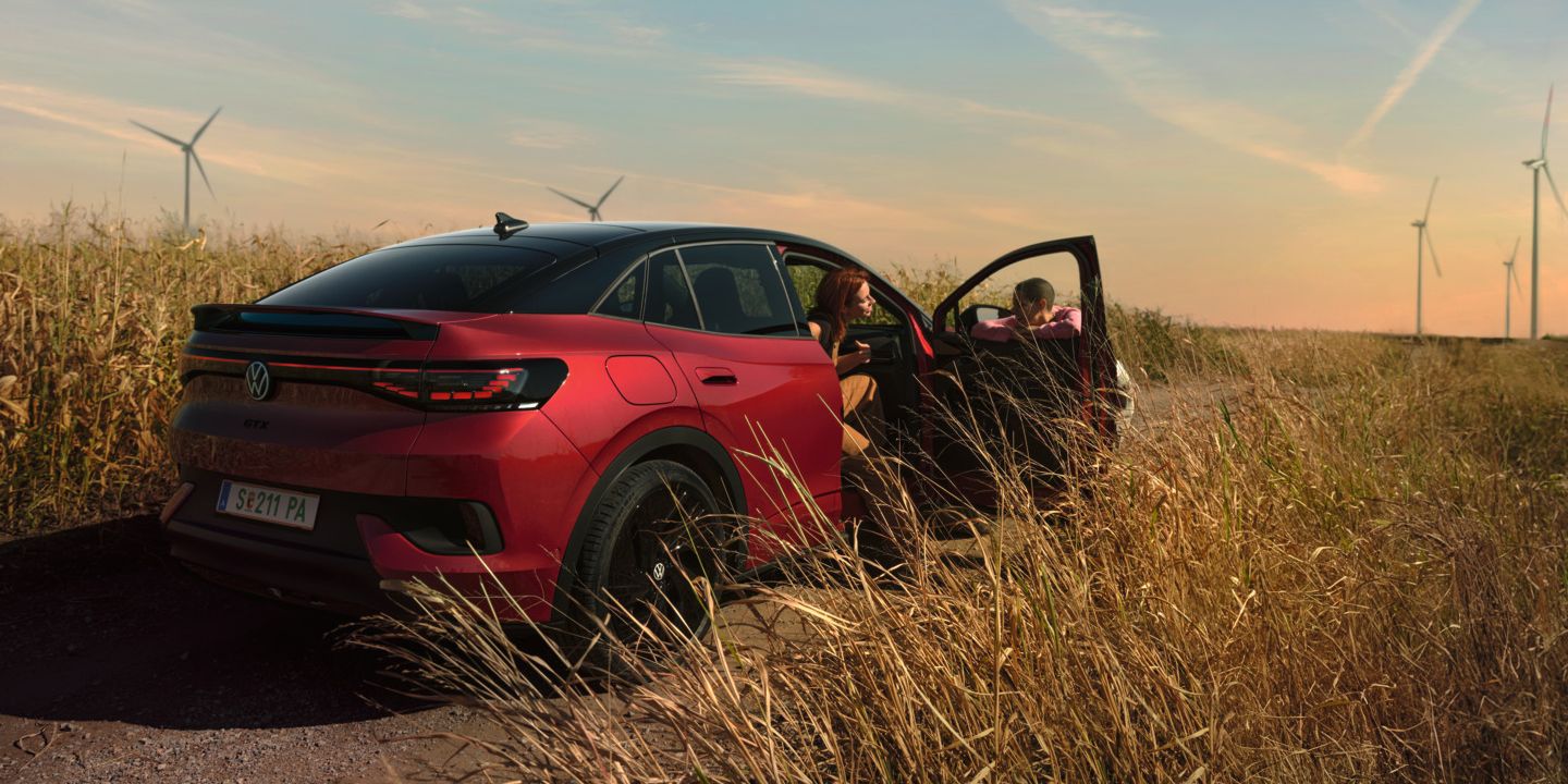 Zwei Personen unterhalten sich neben einem roten ID.5 GTX auf einer Landstraße