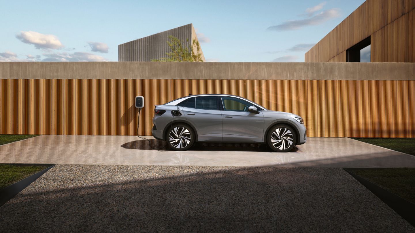 Seitenansicht eines VW ID.5, der vor einem Haus an einer Wallbox geladen wird. 