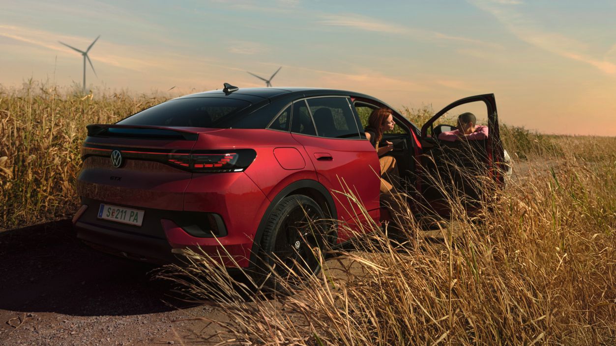 Zwei Personen unterhalten sich neben einem roten ID.5 GTX auf einer Landstraße