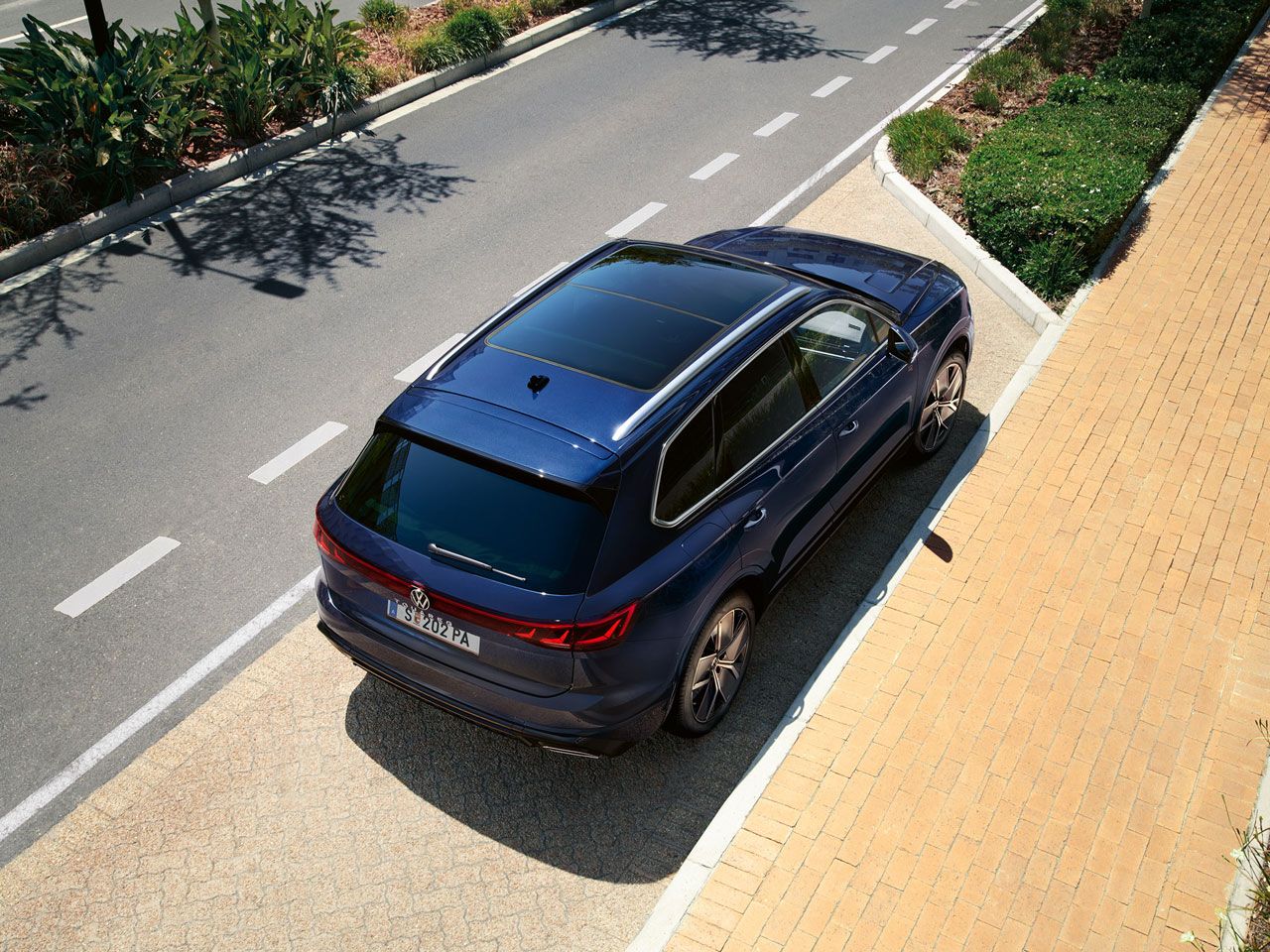 Ein VW Touareg R-Line parkt am Straßenrand, Ansicht von schräg oben auf das Heck und Panoramaglasdach.