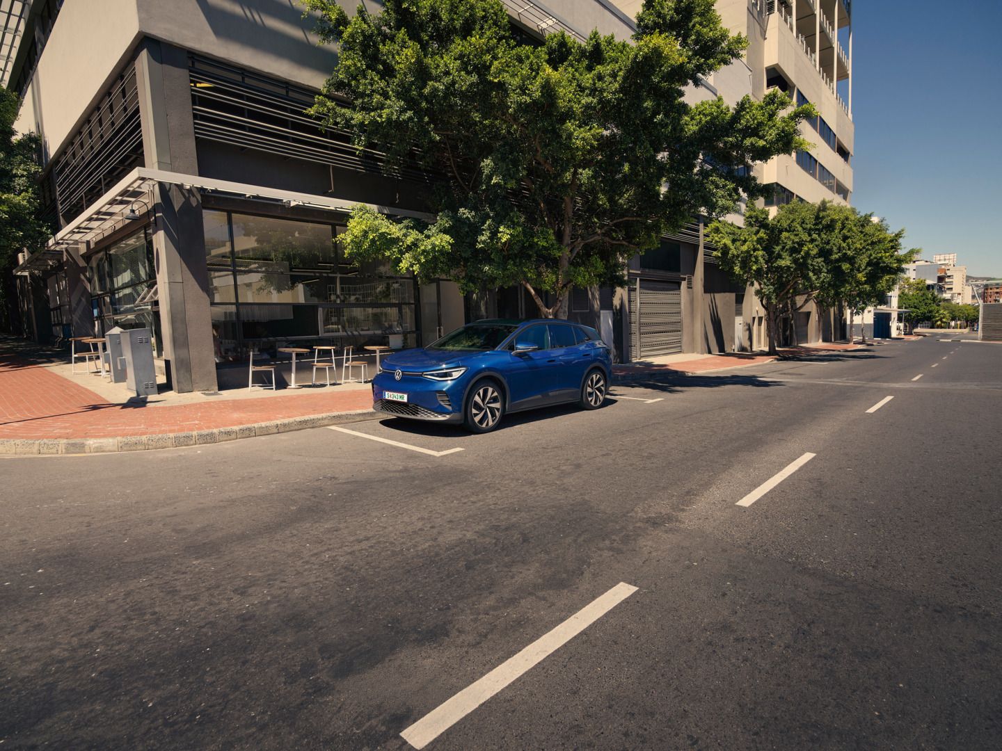 Id.4 steht geparkt neben der Straße vor einem Café in der Stadt.