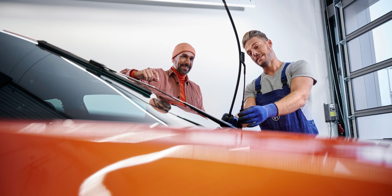 Ein VW Service Techniker wechselt Wischerblätter bei einem Volkswagen