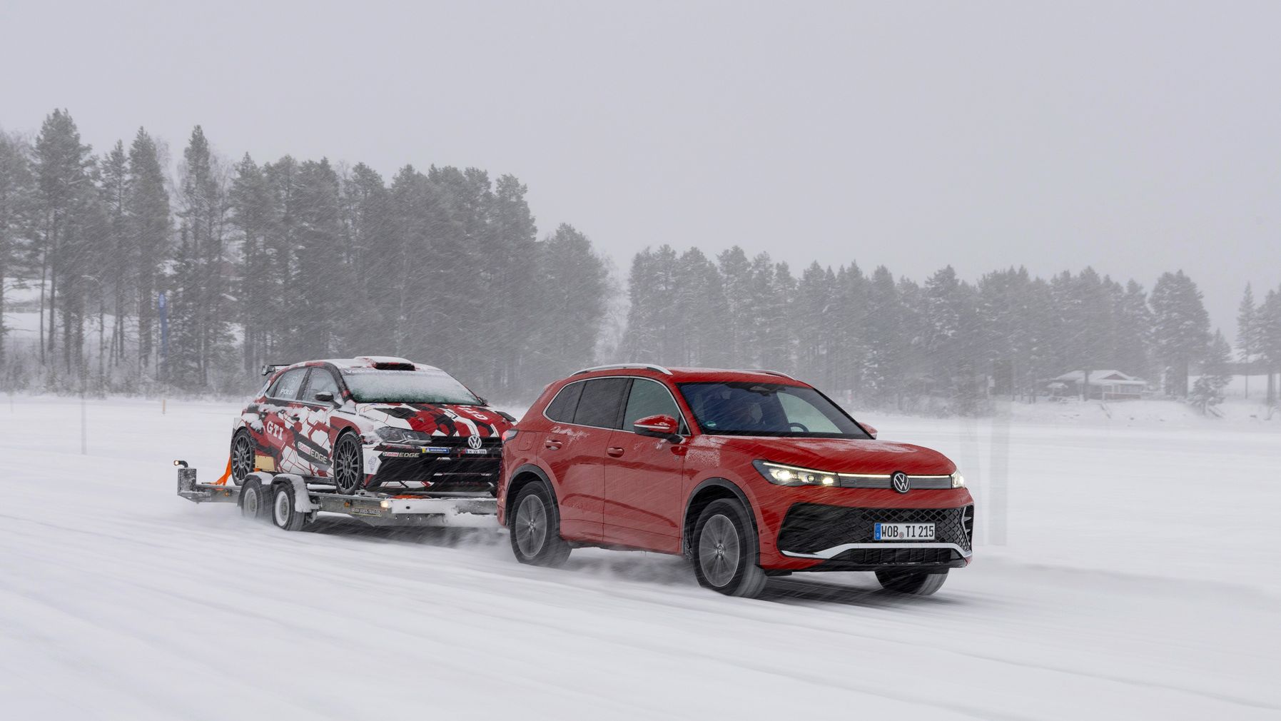 Tiguan fährt auf der Schneestraße mit Anhänger.