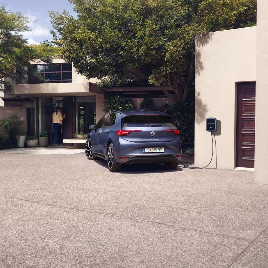 Ein blauer VW ID.3 Neo lädt an einer Wallbox vor einem Einfamilienhaus