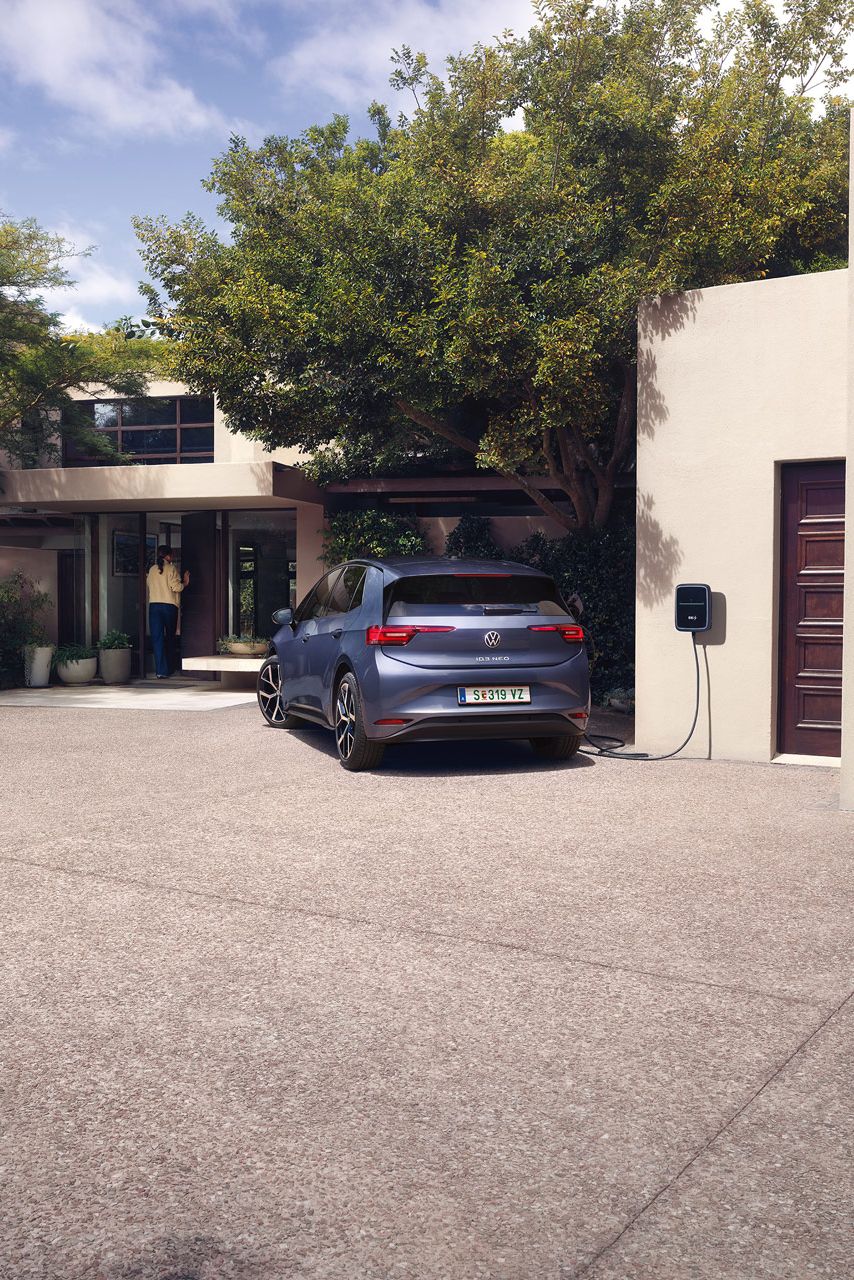 Ein blauer VW ID.3 Neo lädt an einer Wallbox vor einem Einfamilienhaus