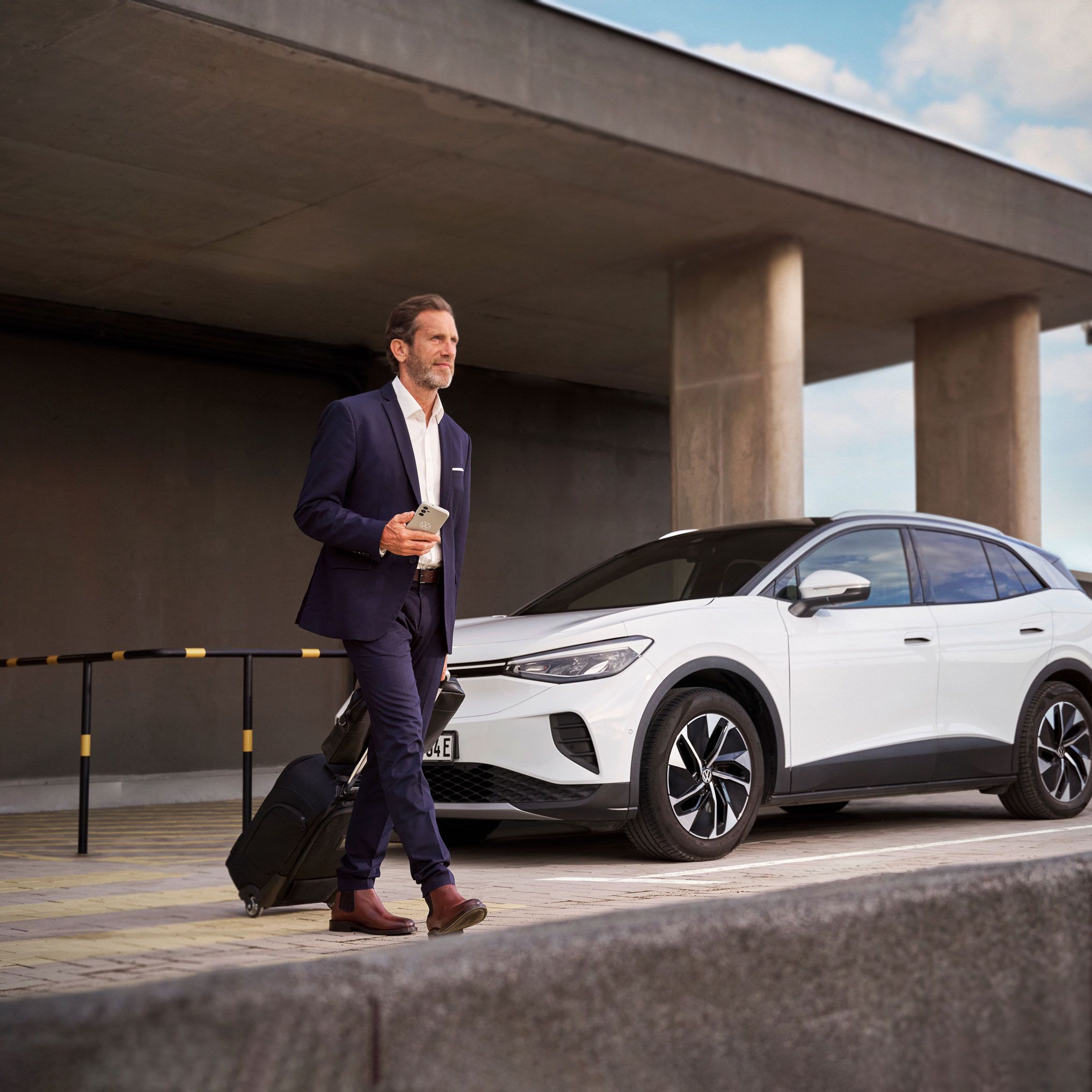 Ein Mann mit einem Koffer geht weg von seinem geparkten ID.4