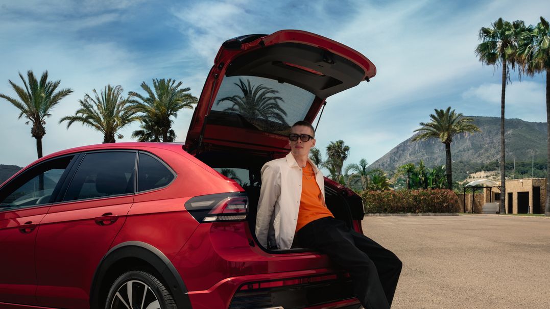 Mann lehnt sich an das Heck des VW Taigo R-Line mit variablem Ladeboden