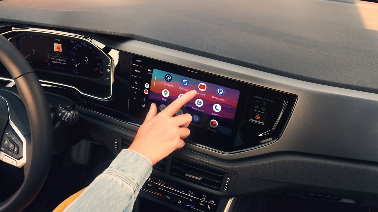 Eine Hand wählt ein App-Symbol im Menü des Infotainment-System eines VW Polo aus.