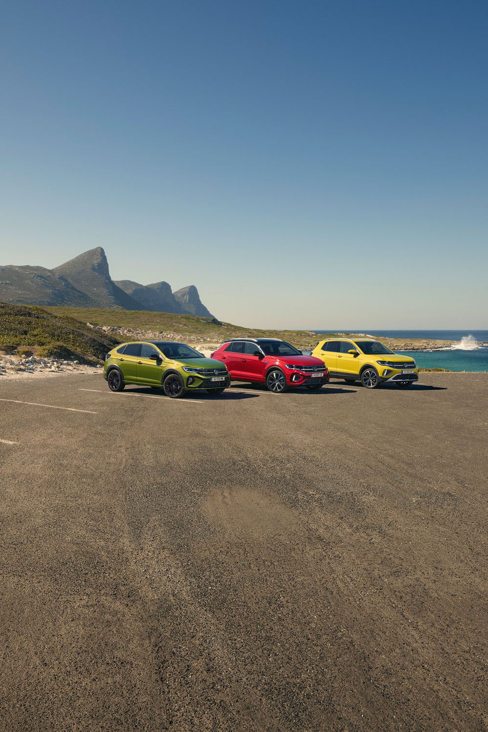 Taigo, T-Roc, T-Cross stehen geparkt auf einem Parkgelände, im Hintergrund sieht man das Meer.