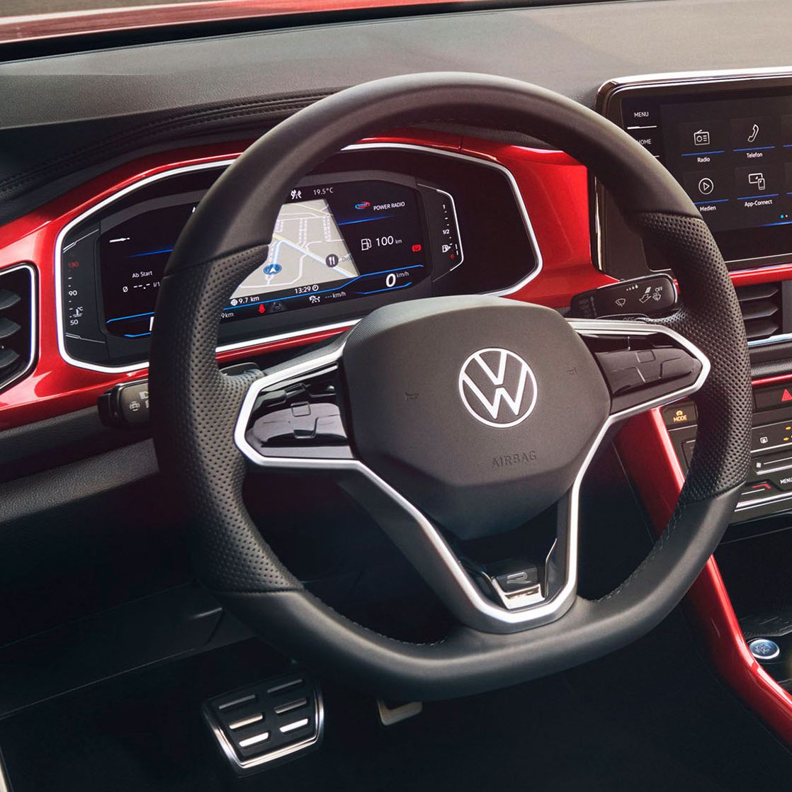 Blick auf das Cockpit des roten T-Roc Cabriolet mit dem Multifunktionslenkrad, Radio und Digital Cockpit.